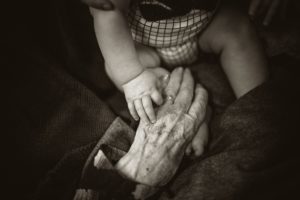 An older woman's hand and a baby, indicating the grandmother of a child born out of wedlock