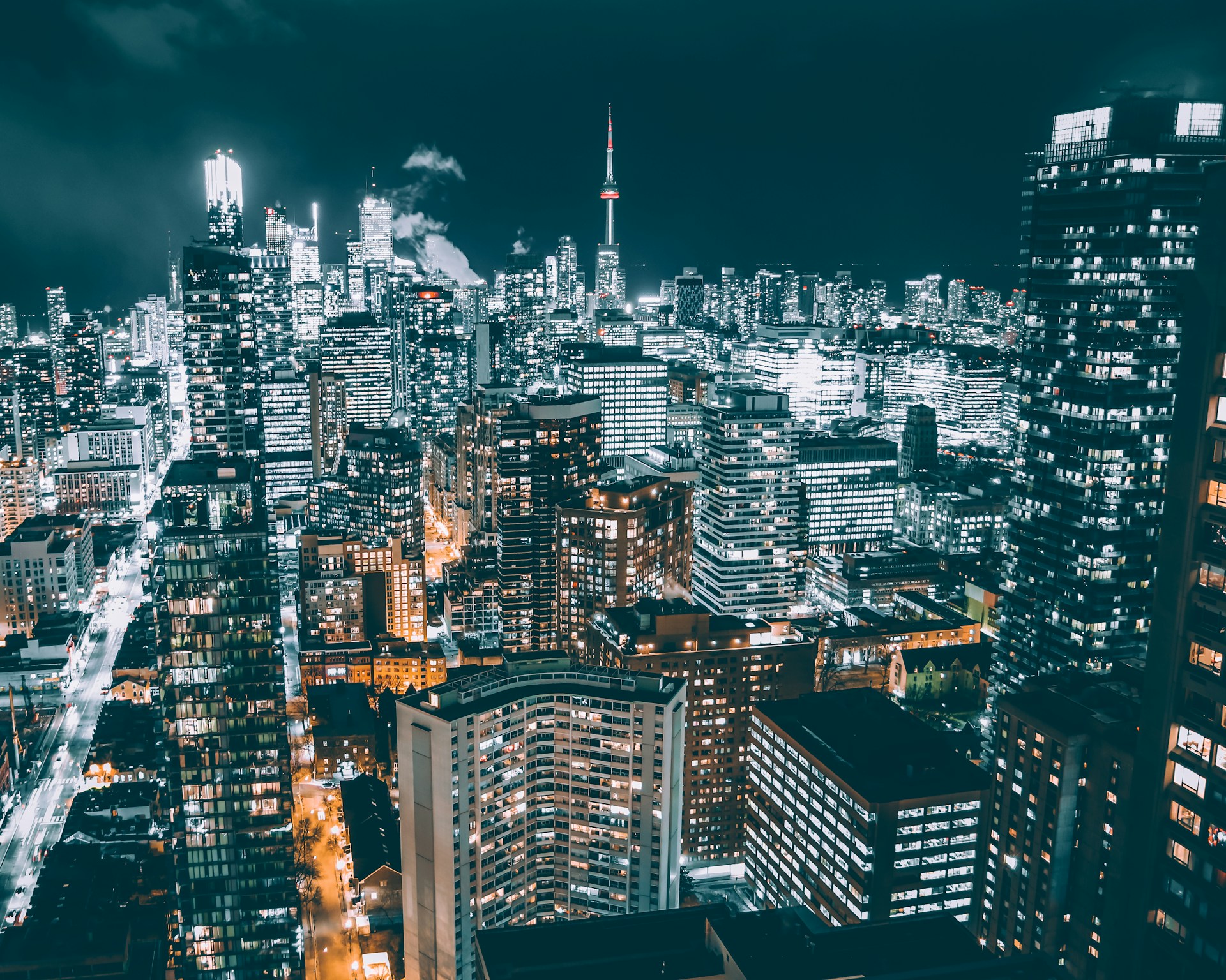 The Toronto skyline at night with the CN Tower, skyscrapers, and office buildings lit up with white lights against the night sky, representing Best Law Firms Canada.