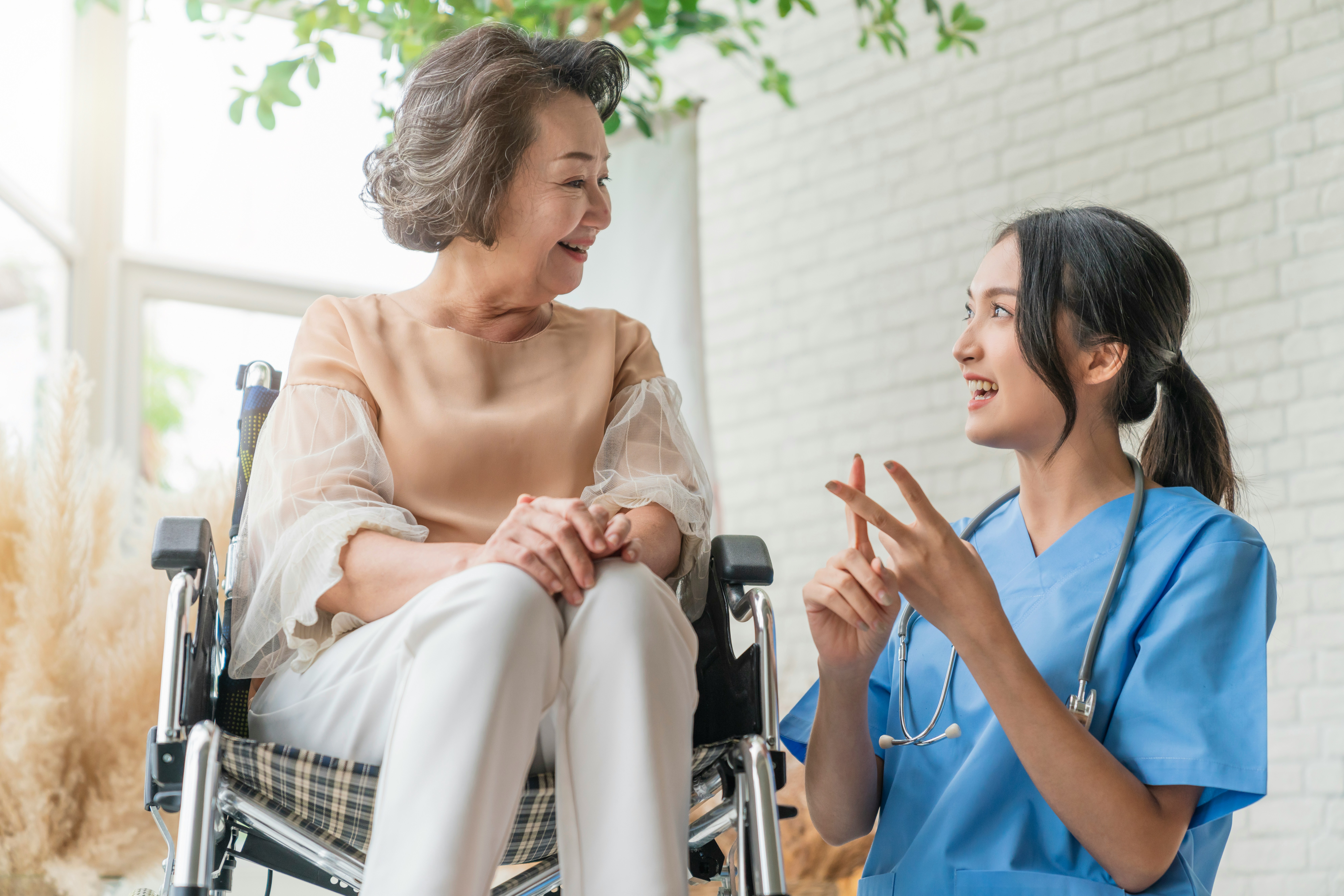 An older woman in a wheelchair speaking with a young nurse at a care home, representing Ontario wills, estates, substitute decision-making, and elder law