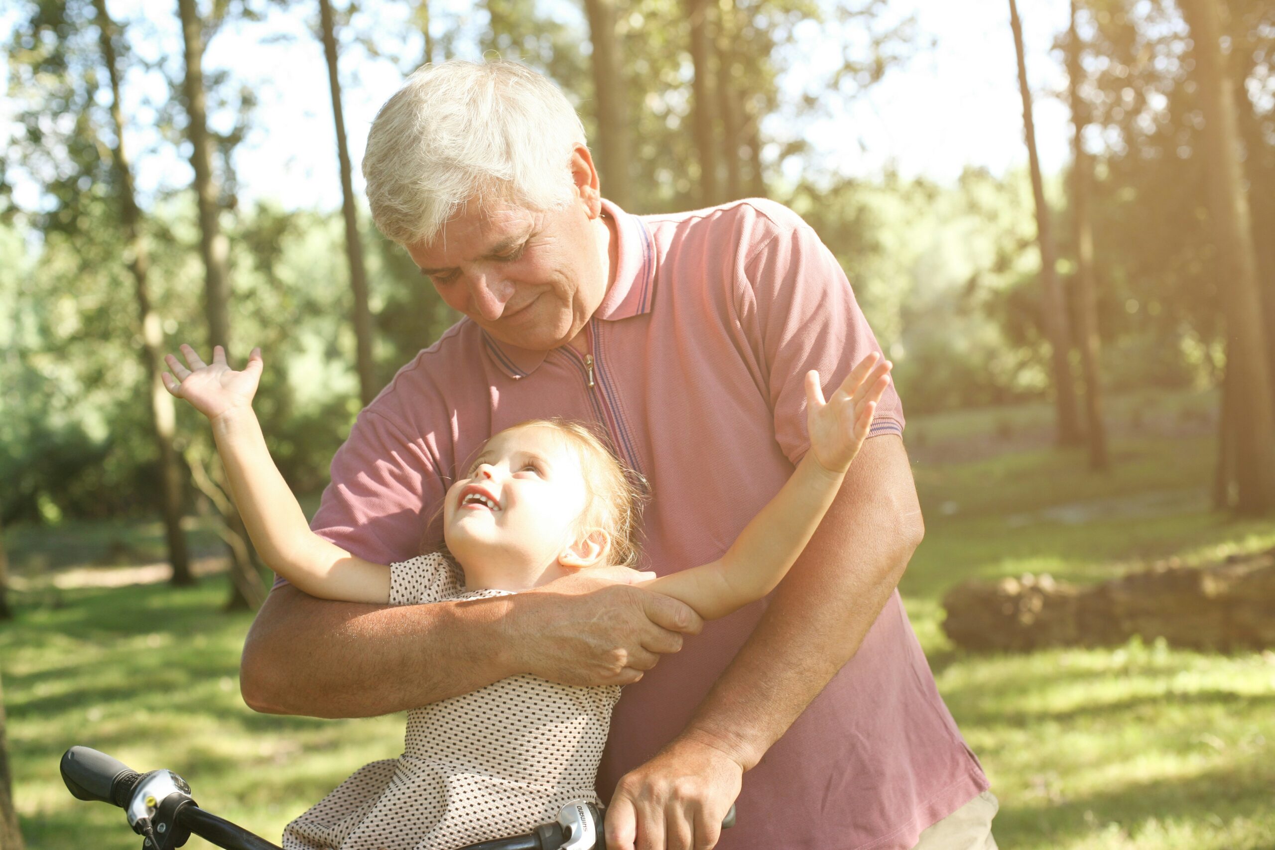 An elderly man hugging his young granddaughter in a sunny park, representing estate and elder law in Ontario