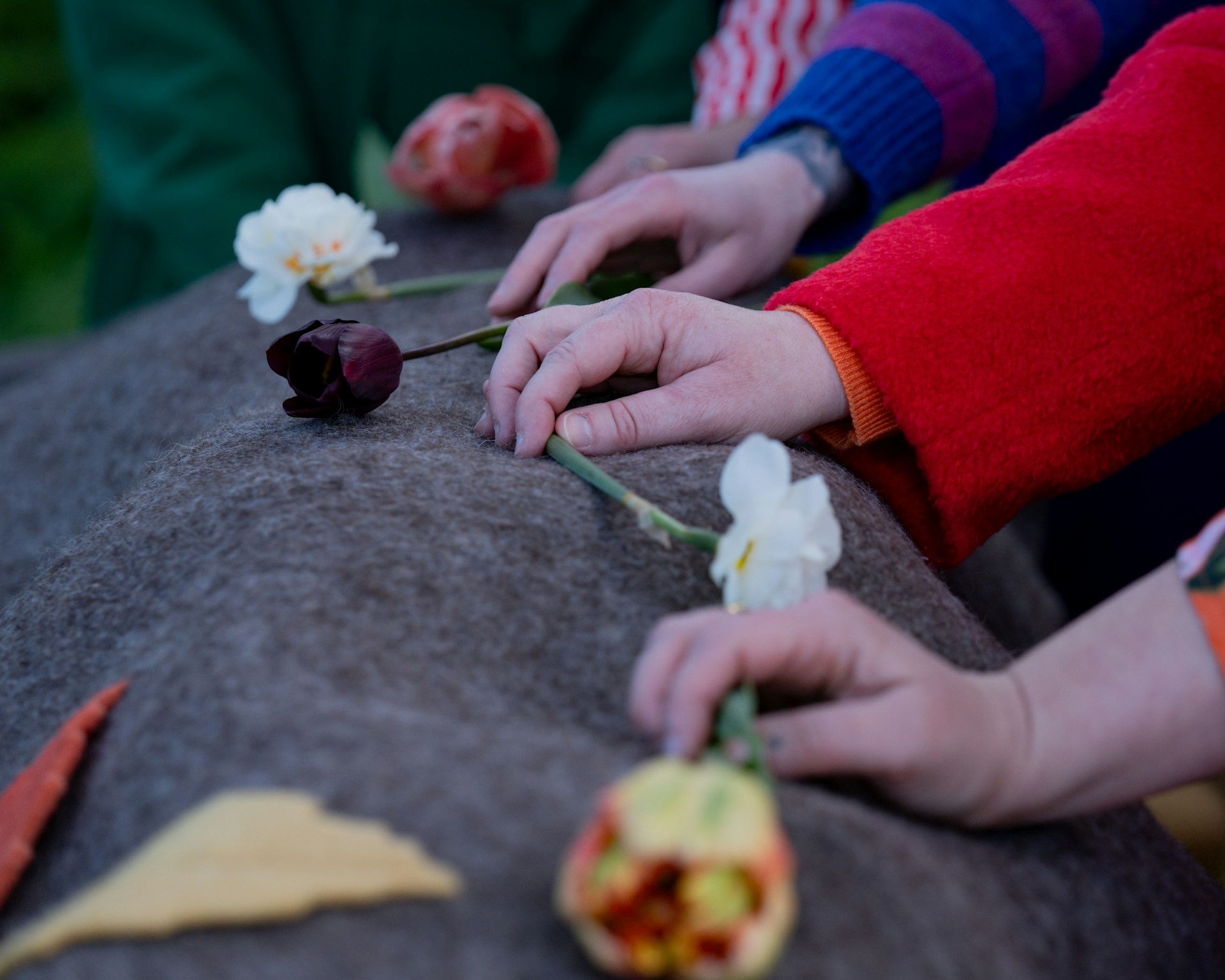 Three people lay flowers on top of grave stone with greenery blurred in the background, representing the abuse of court process in estate litigation.